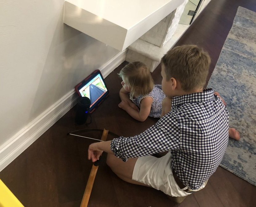 Two kids lying on the floor watching a game on an iPad